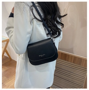Close-up of black leather saddle bag with Fashion Trend embossing and metal buckles