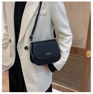 Detail of black PU leather saddle bag featuring white Fashion Trend EST 1996 lettering