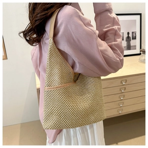 Detail of straw shoulder tote showing woven texture and khaki leather shoulder strap trim