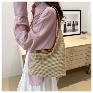 Detailed grid texture of a woven straw tote bag with brown straps in a home setting