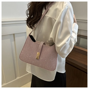 Sac à épaule chic rose pailleté avec fermoir doré porté par un mannequin femme