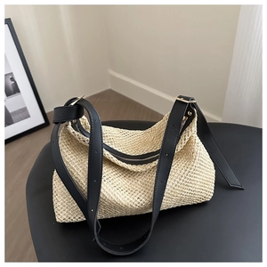 Detailed texture of hand-woven straw tote bag with premium black leather shoulder straps