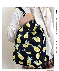 Close-up of black backpack featuring vibrant yellow pineapple prints and a front zipper pocket