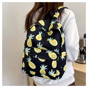Detailed view of black backpack with cute yellow pineapple prints worn by a model