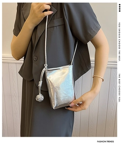 Detail of silver metallic mini crossbody bag with a decorative woven metal ball knot