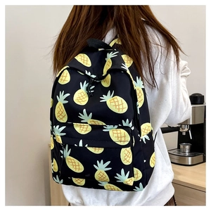 Detail of cute pineapple print canvas backpack shown in a cozy indoor cafe setting