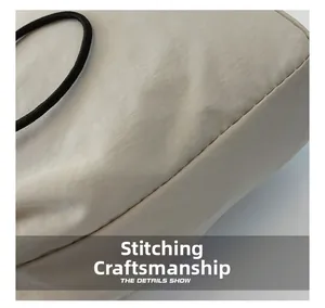Macro shot of precise stitching and black cylindrical handle on the cream canvas bag