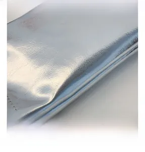 Macro detail of silver metallic textured fabric with neat stitching on a small crossbody bag