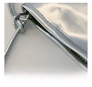 Detail view of precise stitching and metallic silver texture on a mini crossbody bag