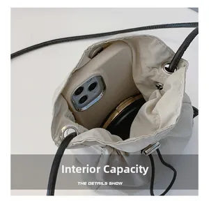 Detail showing internal capacity of the beige mini bucket bag with phone and compact