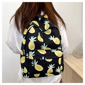 Rear view of a black backpack with cute pineapple print worn by a person against white wall