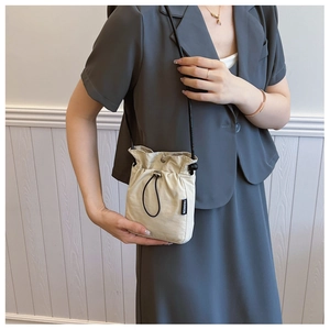 Detail of crossbody phone bag showing fashion label and drawstring closure on fabric