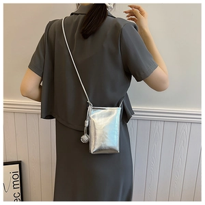 Detail of silver metallic mini crossbody bag with braided tassel and glossy finish