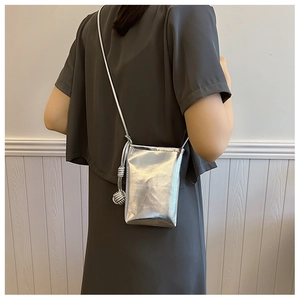Detail of silver metallic mini crossbody bag with knot accent on textured dress