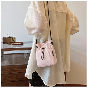 Close-up of light pink drawstring nylon bag with FASHION label and thin black strap