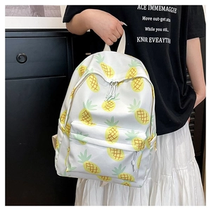 Detailed shot of white canvas backpack with yellow pineapple prints held by a model