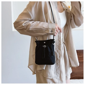Close-up of black nylon drawstring crossbody bag with metallic silver magnetic closure