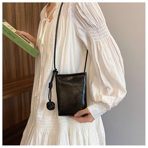 Detail of vintage black crossbody bag in crinkled patent leather with woven ball charm