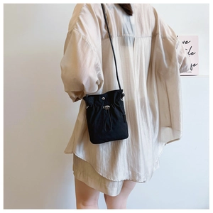 Detail of black drawstring bucket crossbody bag shown on model in Japanese minimalist style