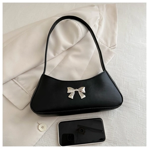 Detail view of black bow baguette bag on a blazer with smartphone for size reference