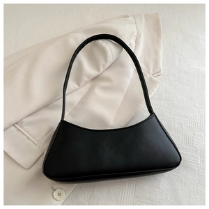 Close-up of black matte bow baguette bag on a white blazer with a minimalist aesthetic