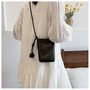 Detail of mini black crossbody bag with textured leather and decorative knot balls