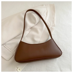 Detailed view of a brown faux leather half-moon baguette bag on a white blazer