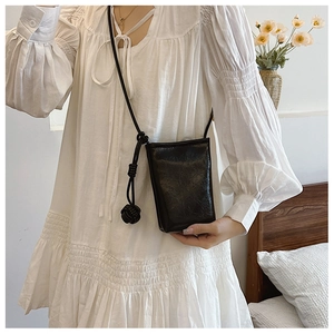 Close-up of black crossbody phone bag with retro pleated texture and knotted strap detail