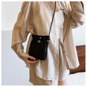 Detail of black drawstring crossbody bag with silver buckle and fashion textile label
