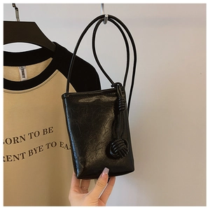 Detail of black glossy leather mobile bag featuring a unique hand-woven knot on the strap