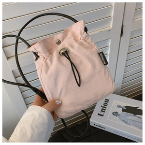 Detail of light pink nylon crossbody bag with drawstring closure and fashion label