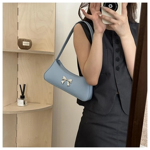 Close-up of a light blue PU leather underarm bag featuring a silver metal bow accent