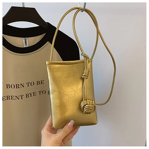 Detail of gold metallic wrinkled leather phone bag with a stylish knot strap design