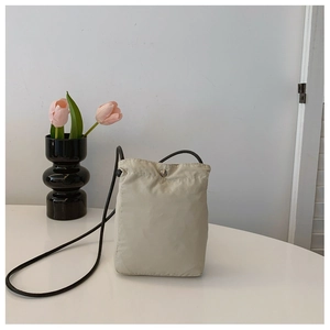 Close-up of minimalist drawstring nylon shoulder bag on table with tulips