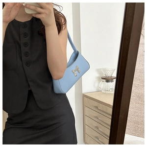 Bolso de axila azul claro con lazo plateado lucido por una modelo con estilo actual