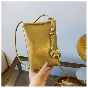 Close-up of golden leather mini bag with wrinkled texture and knotted strap detail
