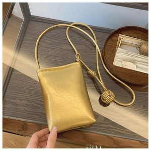 Detail of gold mobile phone bag with wrinkled metallic texture and knotted rope strap