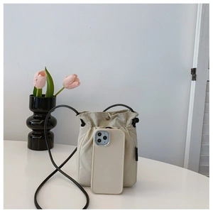 Detailed view of beige mini nylon drawstring bag with phone for scale comparison
