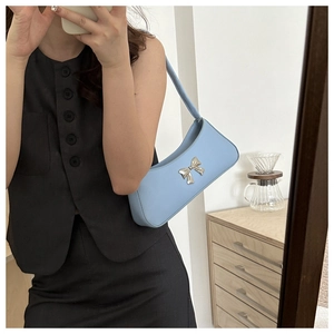 Detail of light blue shoulder bag with silver bow buckle worn on person