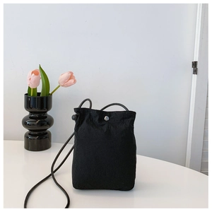 Minimalist black nylon crossbody bag with drawstring strap and metal button detail