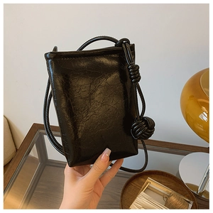 Detail of black oiled leather texture with large knot decoration on the phone bag