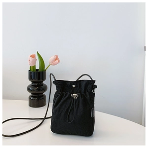 Close-up of black nylon drawstring bucket bag with metal buckle and fashion woven label