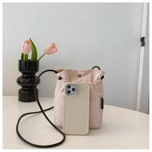 Pink nylon drawstring bucket bag shown next to a smartphone to demonstrate the small size