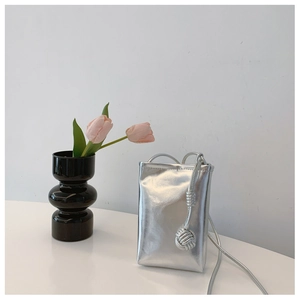 Detail of silver metallic mini crossbody bag with rope strap and knot pendant decor