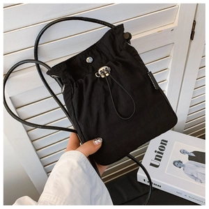 Detail of minimalist black nylon drawstring crossbody bag with silver magnetic snap and tag