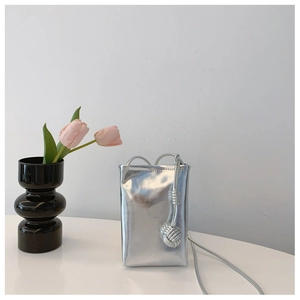 Close-up of stylish metallic silver mini crossbody phone bag with woven strap detail