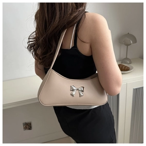 Detail of hobo shoulder bag in cream beige featuring a silver metallic bow accent