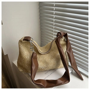 Close-up of woven straw texture and premium brown leather strap on the tote bag