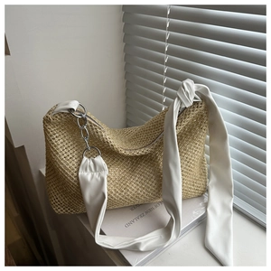 Detail of woven straw shoulder bag with white leather strap and silver chain link