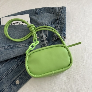 Fashionable fluorescent green oval crossbody bag with chunky chain on denim jacket